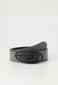 Cinturón de cuero gris con una hebilla ovalada negra que presenta un diseño perforado, textura suave y un ancho estrecho. El extremo se afila ligeramente.