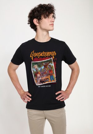 Sort bomulds-T-shirt med teksten "Goosebumps" i orange, med en farverig grafik af skeletter og teksten: "SMIL OG DØ!"