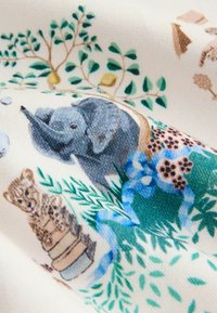 Puuvillakangas, jossa on kuvitetut eläimet, kuten norsu ja tiikeri, ympäröitynä vihreällä kasvustolla ja värikkäillä sinisillä sekä ruskeilla yksityiskohdilla.