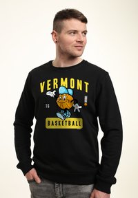 Felpa nera con un personaggio di basket dei cartoni animati che indossa un cappellino blu, con la scritta "VERMONT BASKETBALL" in grassetto giallo.