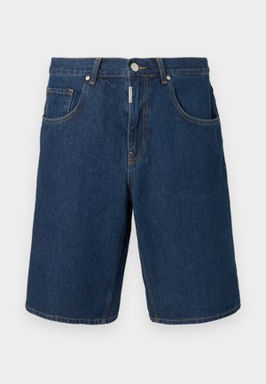 Șort din denim albastru închis cu nasture și fermoar frontal, bucle pentru curea și două buzunare frontale pe un fundal gri simplu.