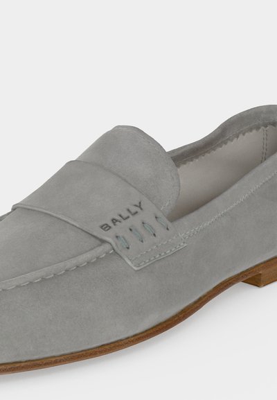 Mocassin en daim gris clair avec semelle marron et logo Bally embossé sur la bride sur le dessus.