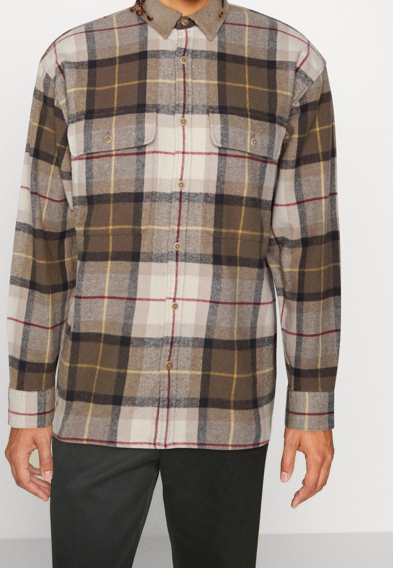 Braun-beiges kariertes Hemd mit Knopfkragen, zwei Brusttaschen und einer weichen Stoffstruktur. Enthält gelbe und rote Linien.
