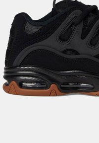 Sneaker neri con una parte superiore testurizzata, ammortizzazione d'aria visibile e una suola in gomma naturale. Presenta dettagli ritagliati e un design elegante.