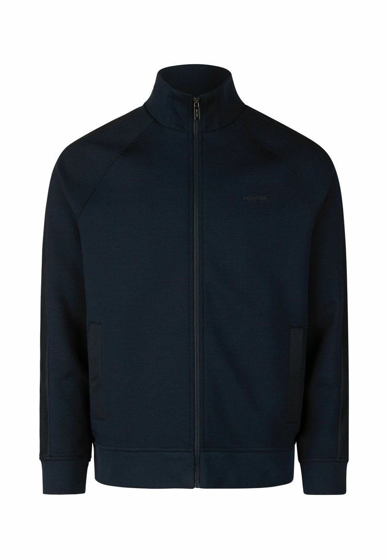 Donkerblauwe ritsjack met hoge kraag, gemaakt van gladde stof. Bevat raglanmouwen en gaasaccenten aan de zijkanten.