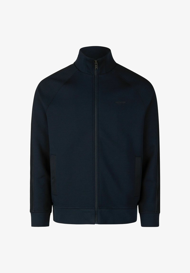 Donkerblauwe ritsjack met hoge kraag, gemaakt van gladde stof. Bevat raglanmouwen en gaasaccenten aan de zijkanten.