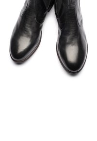 Stivali alla caviglia in pelle nera caratterizzati da una texture liscia, punta affusolata e pannelli laterali elastici. La suola presenta un leggero contrasto di colore.