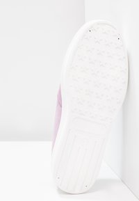 Baskets en daim rose avec une semelle en caoutchouc blanche affichant un motif étoilé. La chaussure est vue de côté, mettant en avant son bout arrondi et sa texture lisse.