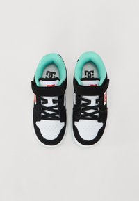 Zapatillas en blanco y negro con un interior de color verde menta, con cordones y una correa de Velcro, fabricadas con materiales sintéticos.