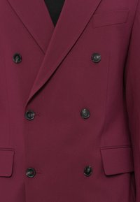 Blazer doppiopetto borgogna realizzato in tessuto liscio, con bottoni neri, una tasca sul petto e un design a rever.