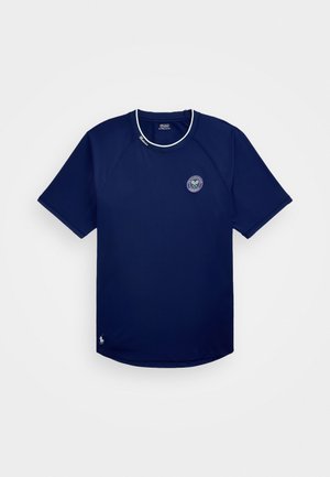 Temno modra športna majica s kratkimi rokavi, okroglim izrezom in belimi detajli. Ima krožni logotip in majhen vezen akcent na robu.