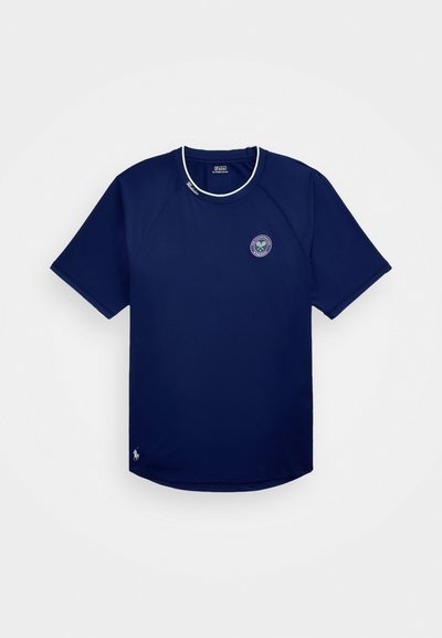 Camisola atlética azul-marinho de mangas curtas, com decote redondo e detalhes brancos. Apresenta um logotipo circular e um pequeno detalhe bordado na bainha.