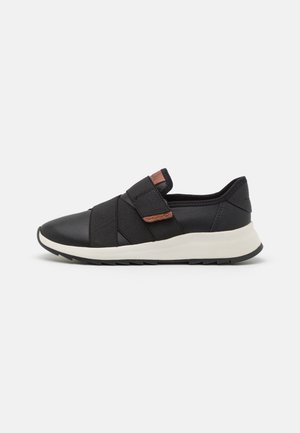 Sort slip-on sneaker med elastiske stropper og brune læderdetaljer, med en hvid polstret sål og en rillede sort ydersål.