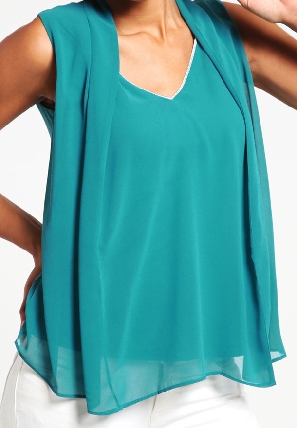 Haut sans manches teal en tissu léger et transparent, avec un design en v et un superposition ouverte dévalant vers le bas. Accents blancs visibles.