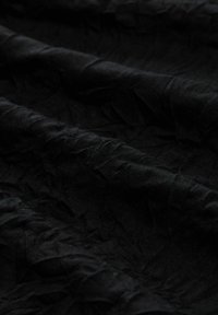 Schwarzer, zerknitterter Stoff mit einer strukturierten Oberfläche, der weiche Falten und ein matte Finish aufweist. Geeignet für verschiedene Bekleidungs- oder Polsteranwendungen.