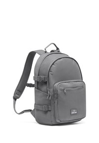 Rucsac din material gri, cu bretele căptușite, maner pe partea de sus, buzunar frontal cu fermoar, buzunare laterale și accesorii cu catarame ajustabile. Textură netedă.