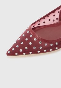 Chaussure en tissu bordeaux avec un bout pointu, dotée d'une inset en maille et ornée de strass ronds et transparents sur toute la surface.