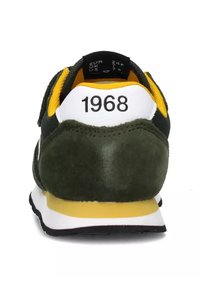Scarpa sportiva in suede verde con una sezione del tallone bianca. Presenta una foderatura in tessuto giallo e dettagli neri, con "1968" stampato sul retro.