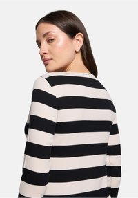 Zwart-witte gestreepte langemouwen top met een ronde halslijn, met een fitted ontwerp en ribbelstructuur overal.