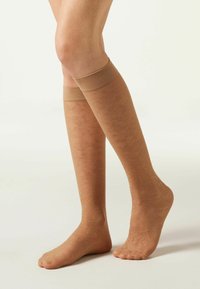 Hudfärgade knästrumpor i transparent material, med ett subtilt blomm�önster. Den övre delen är slät och ger en bekväm passform.