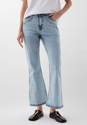 Jeans svasati azzurri chiari con vita alta, caratterizzati da una texture sottile e cuciture a contrasto, rifiniti con orlo frangiato.