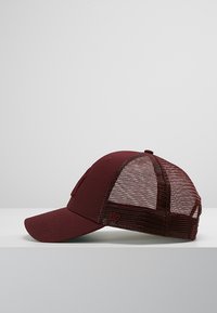 Cappello bordeaux con parte frontale solida e retro in rete, caratterizzato da una visiera curva e un logo ricamato dello stesso colore, mostrato di lato.