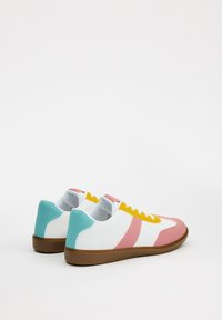 Zapatillas blancas con detalles en rosa, azul claro y amarillo. Parte superior de sintético suave, paneles texturizados y suela de goma marrón.