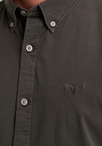 Camicia button-up grigia scura in cotone. Presenta un colletto classico, dettagli cuciti e un logo con ali ricamato sul petto.