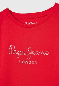 Czerwona bawełniana koszulka z okrągłym dekoltem, ozdobiona logo "Pepe Jeans London" w dekoracyjnych srebrnych ćwiekach.