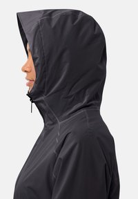 Giacca nera impermeabile con cappuccio aderente, texture liscia e cuciture visibili. Cerniera con zip a tirante posizionata sul davanti.