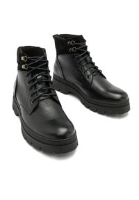 Czarne skórzane botki z teksturowaną powierzchnią, wysokość do kostki, płaska gumowa podeszwa, metalowe oczka i sznurówki w kontrastowym kolorze.
