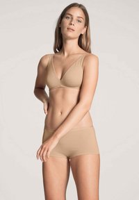 Beige seamless beha met verstelbare banden en een bijpassende boyshort. Gladde textuur, minimalistisch ontwerp, met een focus op comfort en veelzijdigheid.