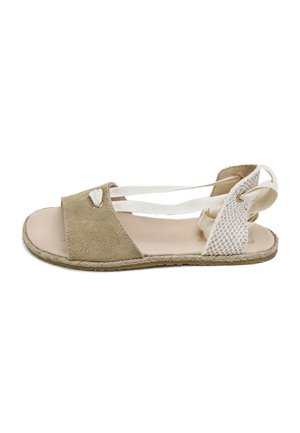 Sandalia beige de punta abierta con tira frontal de ante, tira trasera tejida y lazos blancos cruzados en el tobillo sobre una suela plana.