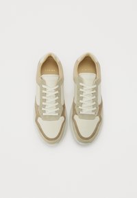 Sko med en beige og kremfargekombinasjon, som har en blanding av glatte og semskede overflater, rund tå, snøring og minimal merking.