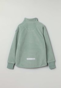 Vihreä fleece-pullove, jossa on korkea kaulus, raglan-hihat, ribatulla hihansuilla ja alareunassa valkoinen etiketti, jossa on brändin nimi.