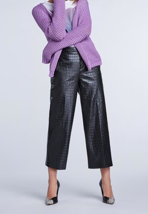 Cardigan lilac in maglia, pantaloni cropped neri in pelle sintetica con texture a coccodrillo e tacchi neri con accenti argentati.