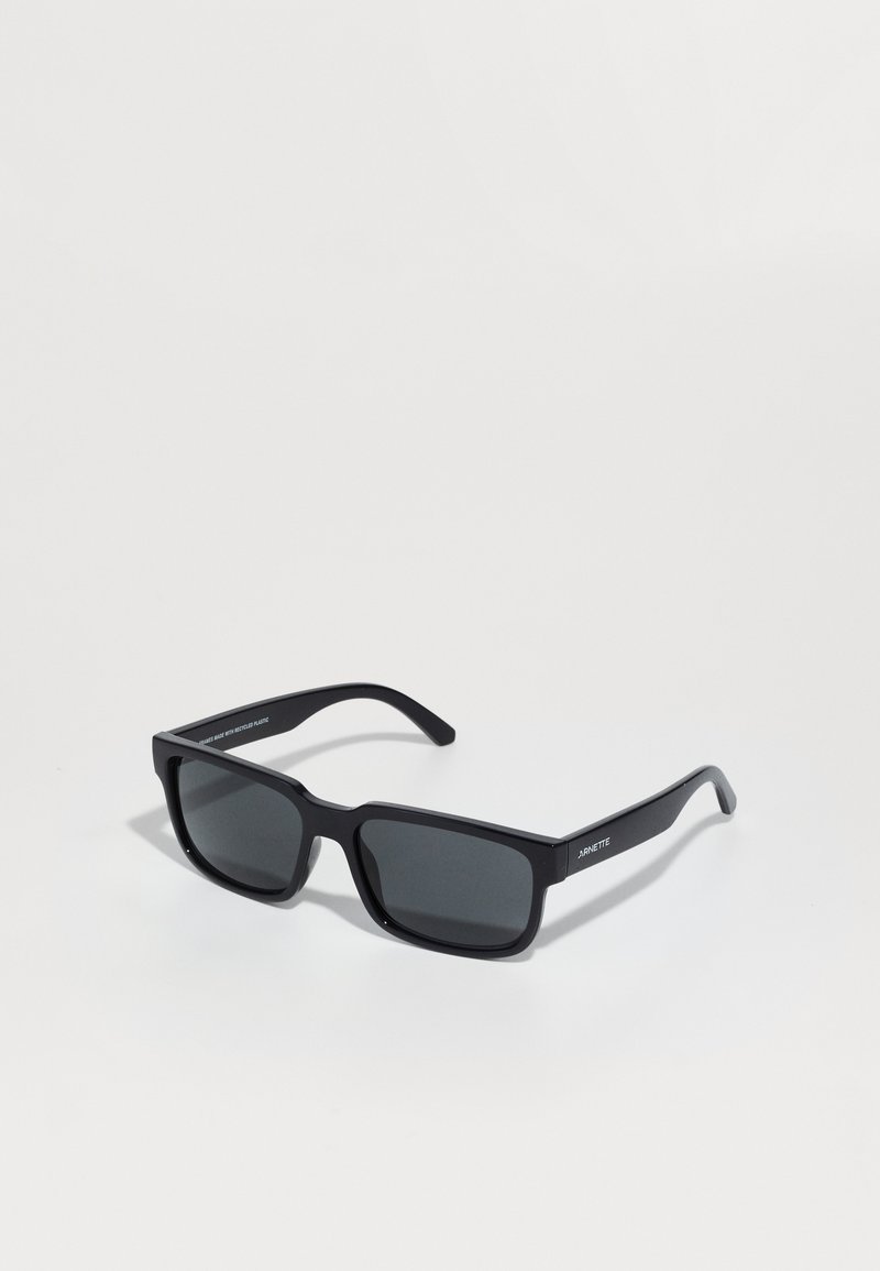 Gafas de sol rectangulares negras con lentes oscuros, fabricadas en plástico. Presentan un diseño elegante con varillas sutilmente curvadas.