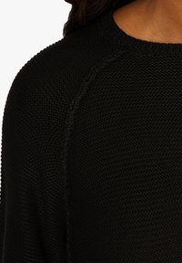 Černý pletený svetr s texturovaným vzorem, žebrovaným výstřihem a raglánovými rukávy pro pohodlný střih. Vyrobeno z měkké látky.