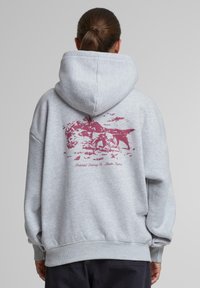 Šedá mikina s kapucňou, na chrbte s marónovým grafickým dizajnom zvierat. Štruktúrované manžety a spodný okraj, vyrobená z textílie z bavlneného zmesi.