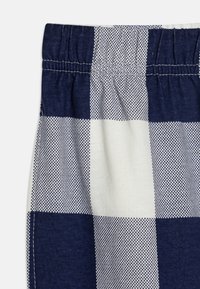 Námornícka a biela kockovaná tkanina s hladkým povrchom; obsahuje elastický pás a bodkovaný vzor v striedajúcich sa štvorcoch.