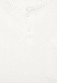 White cotton henley shirt featuring a round neckline, three buttons, and a chest pocket with a textured fabric.