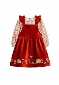 Rote Corduroy-Latzkleid mit einem langärmeligen, blumigen Oberteil. Es hat rüschenbesetzte Träger und bestickte Igel und Blumen am Saum.