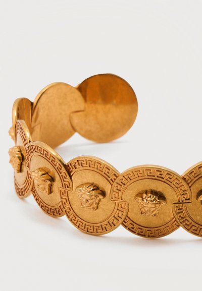 Χρυσό βραχιόλι αποτελούμενο από συνδεδεμένους στρογγυλούς μενταγιόν με ανάγλυφα κεφάλια Μέδουσας και μοτίβα ελληνικού κλειδιού σε λευκό φόντο.