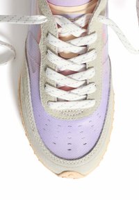 Zapatilla de malla lila claro con detalles en ante gris, puntera redonda, cuello acolchado y cordones en contraste. Suela texturizada en beige.