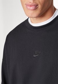 Svart sweatshirt i mjuk kvalitet, med rund halsringning och broderad Nike-logotyp i svart på bröstet. Enkelt, minimalistiskt design.