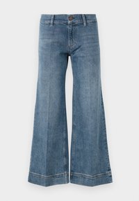 Jean en denim bleu à jambes larges avec passants de ceinture, fermeture à bouton et détails de couture visibles sur un fond blanc.