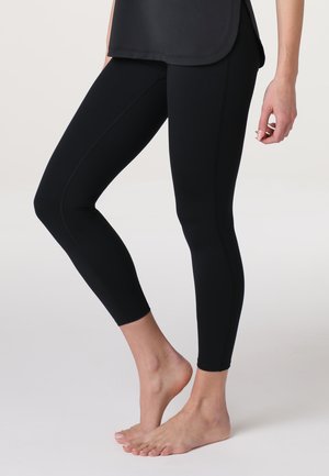 Leggings neri realizzati in materiale elastico, design aderente, che arrivano a metà polpaccio. Presentano una linea di cucitura pulita senza ulteriori decorazioni.