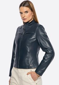 Navy Lederjacke mit hohem Kragen, Frontreißverschluss, zwei Brusttaschen und Seitentaschen; glatte Textur und taillierte Passform.