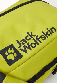 Groene waterdichte rugzak met een gestructureerd oppervlak. Voorzien van een groot zwart logo en pootafdruk, verstevigde ritsen en zwarte accenten.
