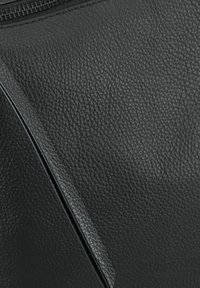 Czarna torba skórzana o teksturowanej powierzchni z gładkim suwakiem, charakteryzująca się subtelnym geometrycznym kształtem i precyzyjnym przeszyciem wzdłuż krawędzi.